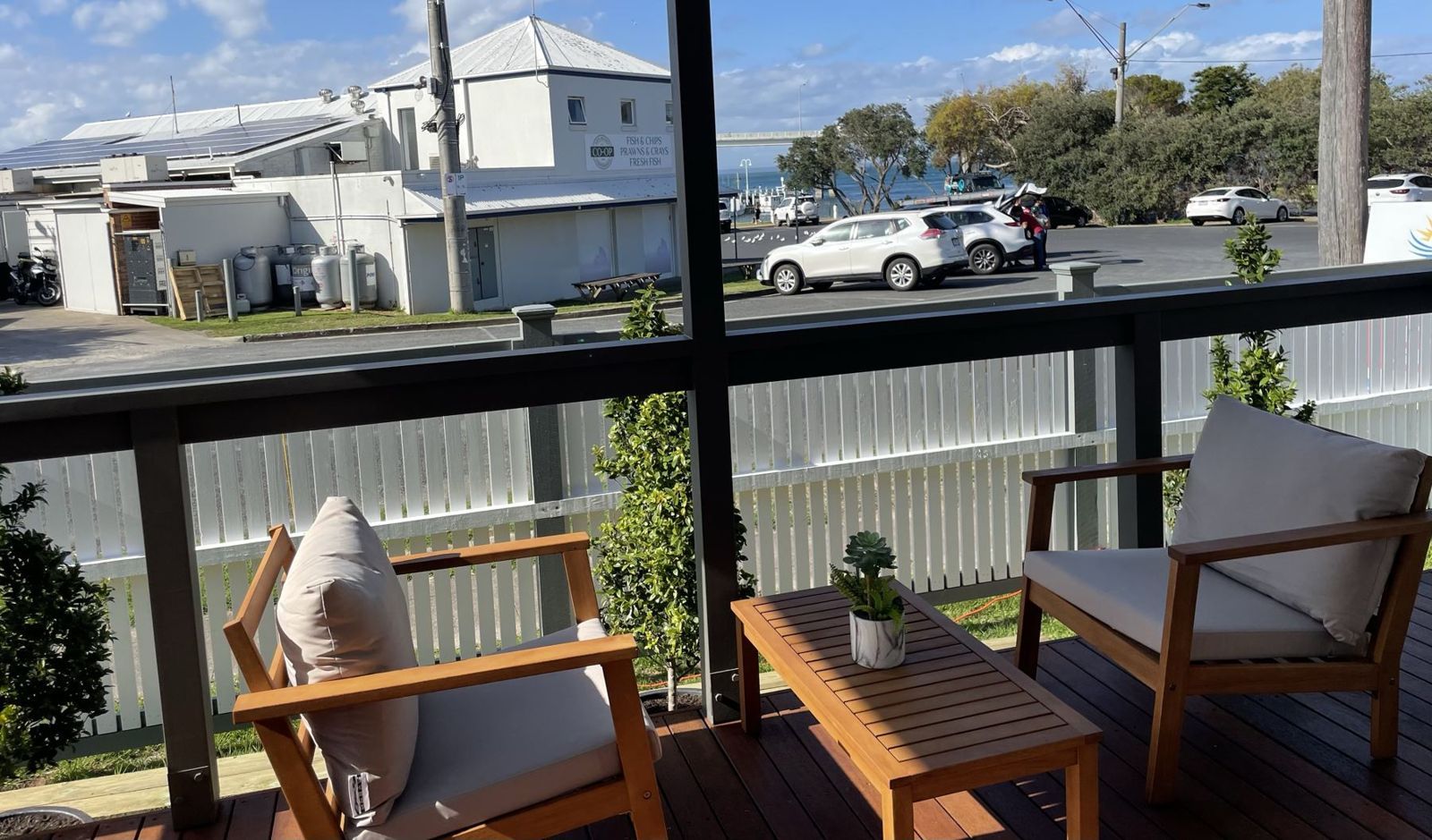 Balcony with timber outdoor chairs looking over the street towards the harbour