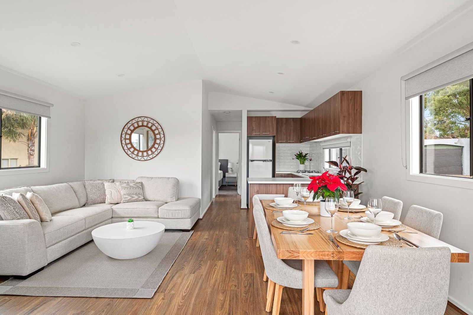 Open-plan living and dining with timber floors, corner lounge and six-seat table